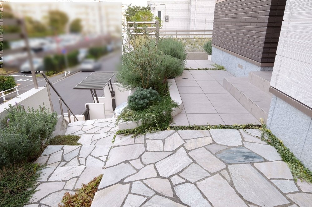 両脇に植栽の植わった花壇を楽しみながら、乱形石貼り階段を上がって玄関へ